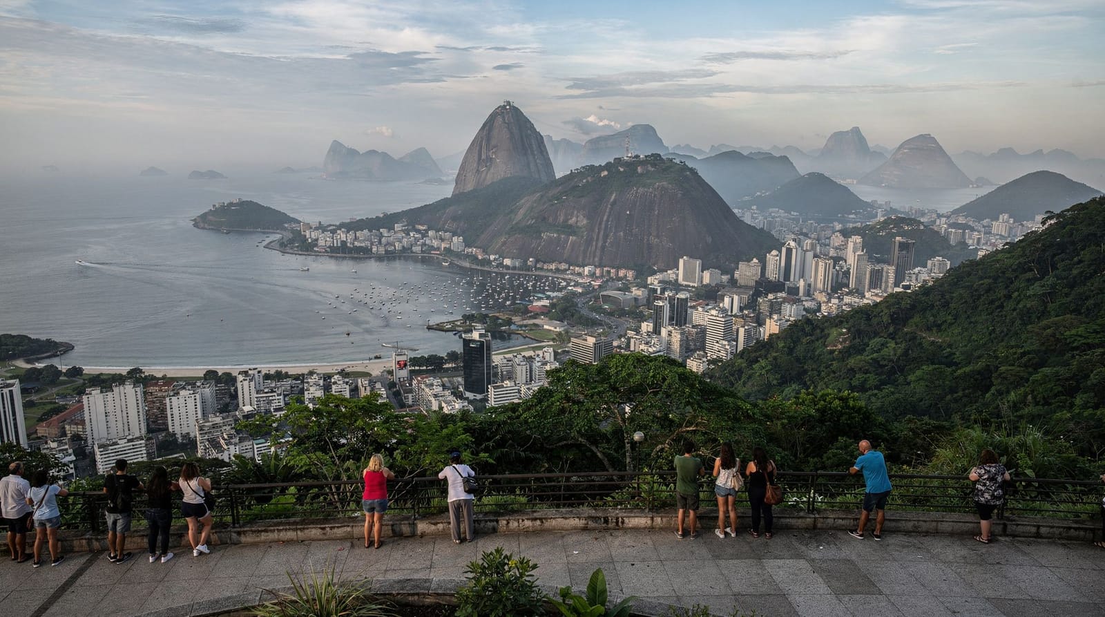 Christ the Redeemer overlooking Rio de Janeiro at dusk, with Sugarloaf Mountain and Guanabara Bay in the distance
